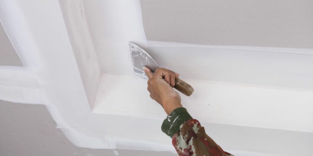 hand of worker using gypsum plaster ceiling joints at construction site